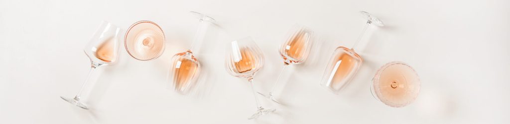 Rose wine variety layout. Flat-lay of rose wine in various glasses over plain white background, top view. Summer drink for party, wine shop or wine tasting concept